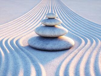 pile of smooth stones balancing on top of each other surrounded by textured sand
